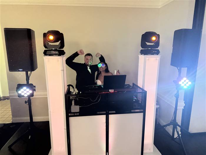 DJ celebrating with bride and groom behind the DJ booth