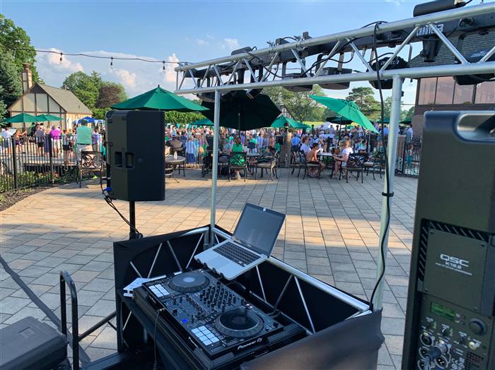 Outdoor pool party event with a crowd and DJ truss