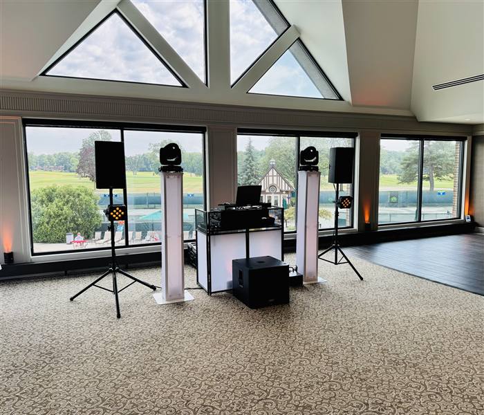Minimal DJ setup in a glass-walled golf club ballroom