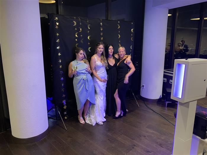 Guests posing at a neon photo booth backdrop